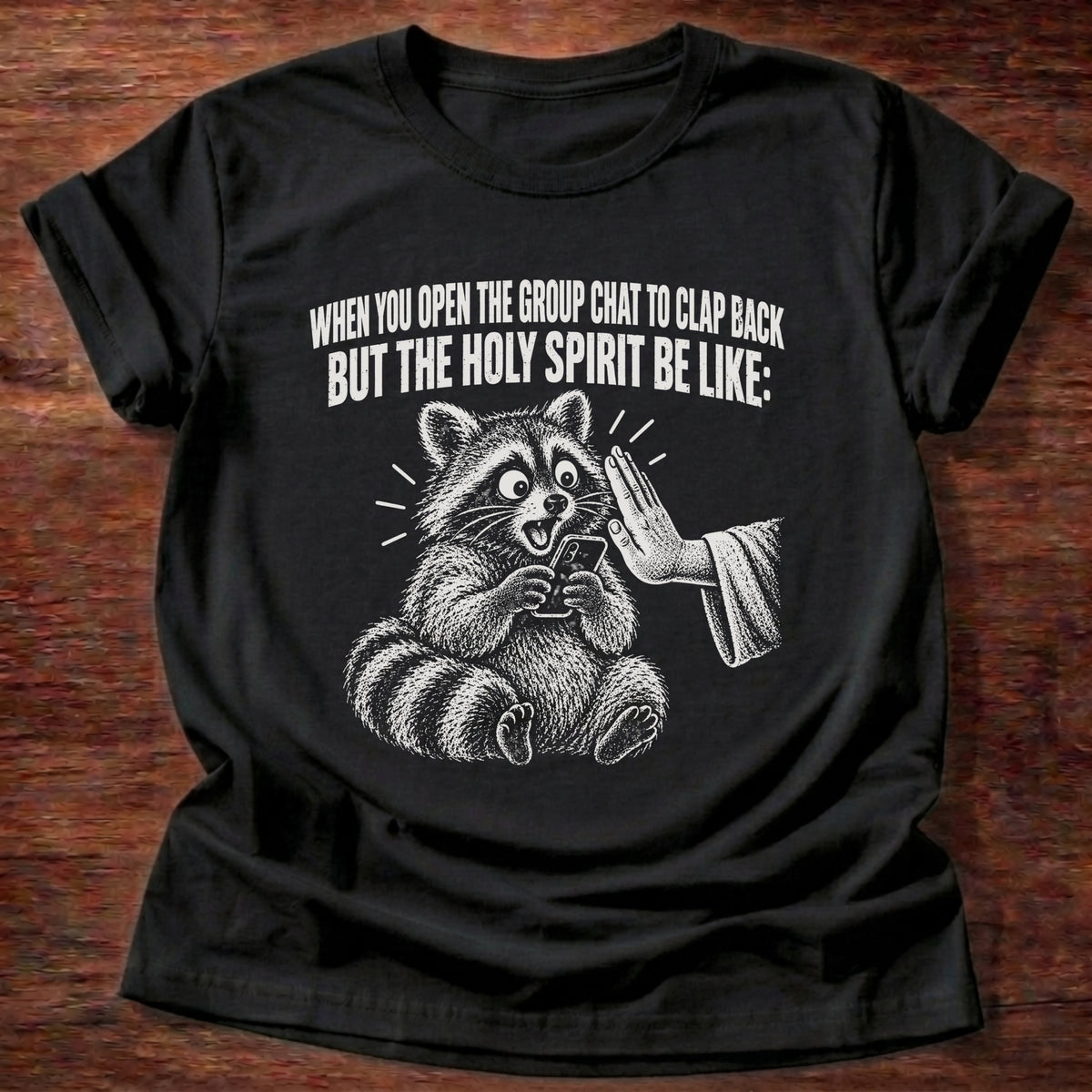Black t-shirt printed with a raccoon covering its own mouth graphic and 'When you open the group chat to clap back but the Holy Spirit be like.' Proverbs 21:23 faith based gift