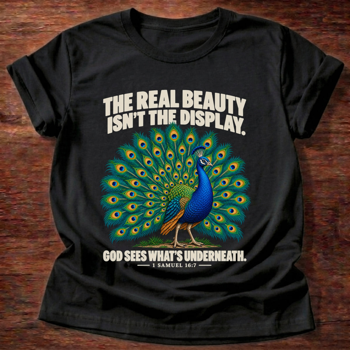 Black t-shirt printed with a peacock with feathers in full display graphic and 'The real beauty isn't the display. God sees what's underneath.' 1 Samuel 16:7 faith based gift