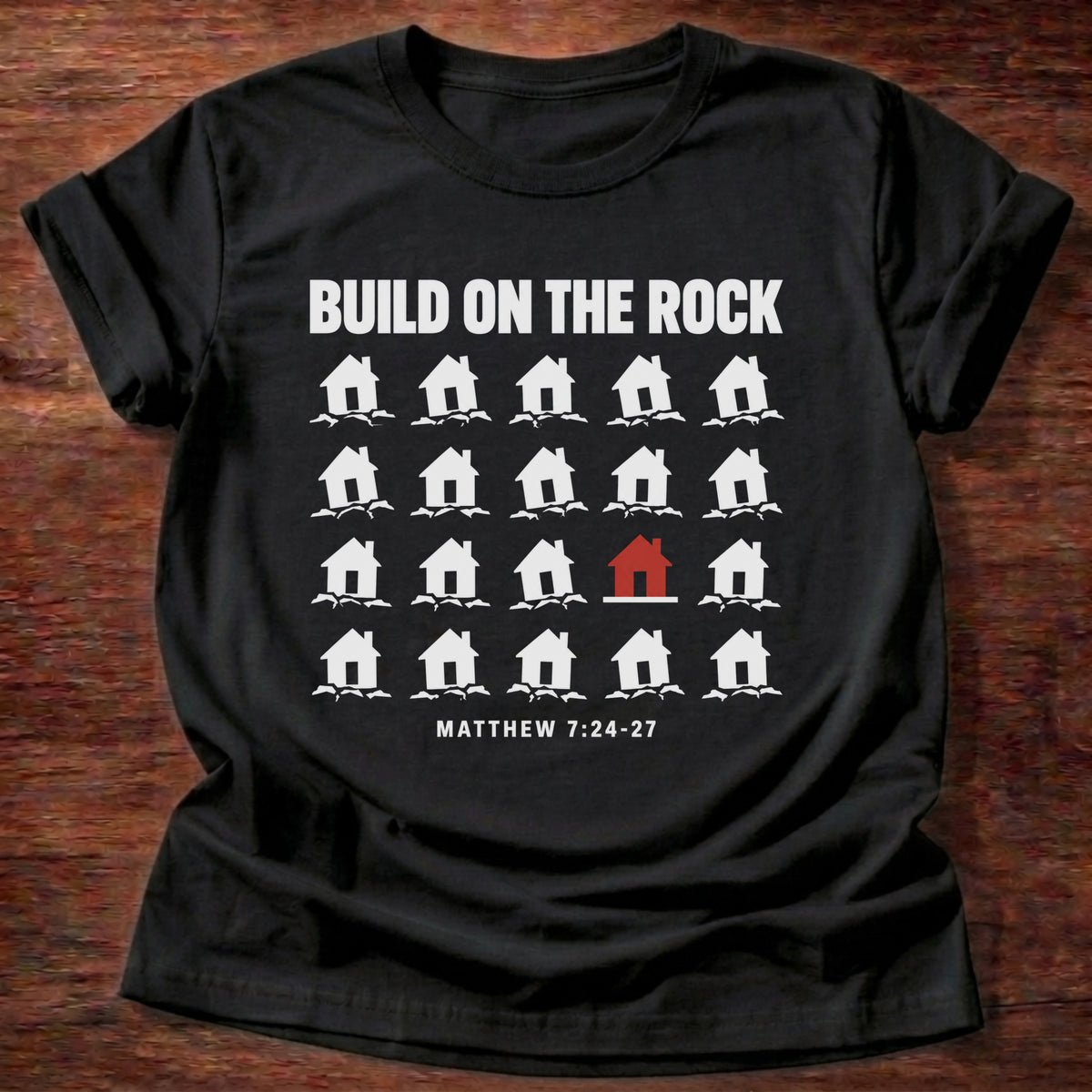 Black t-shirt printed with a row of houses graphic and 'Build on the rock.' Matthew 7:24-27 faith based gift