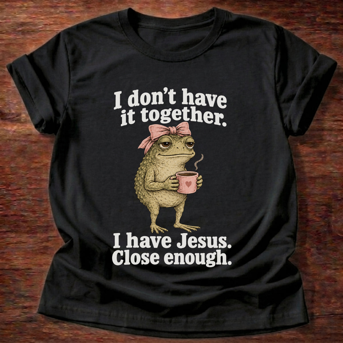 Black t-shirt printed with a frog holding a tea cup graphic and 'I don't have it together. I have Jesus. Close enough.' 2 Corinthians 12:9 faith based gift