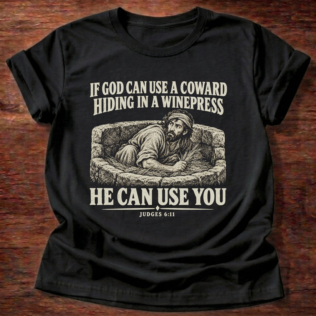 Black t-shirt printed with Gideon hiding in a winepress graphic and 'If God can use a coward hiding in a winepress, He can use you.' Judges 6:11 faith based gift