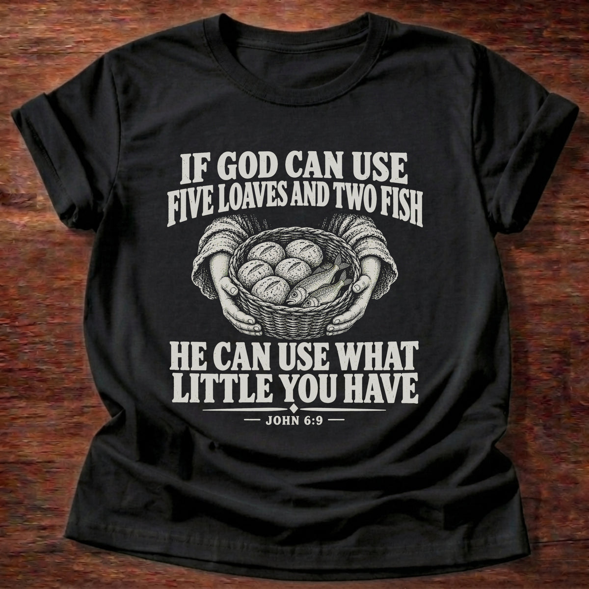 Black t-shirt printed with a basket of loaves and fish graphic and 'If God can use five loaves and two fish, He can use what little you have.' John 6:9 faith based gift