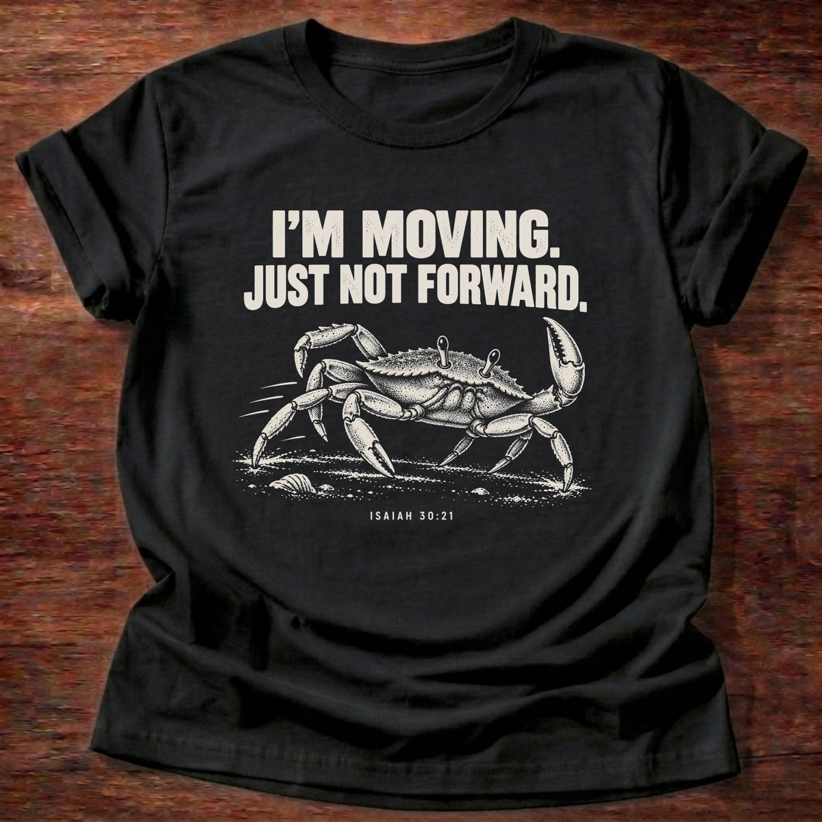 Black t-shirt printed with a crab scuttling sideways across the sand graphic and 'I'm moving. Just not forward.' Isaiah 30:21 faith based gift