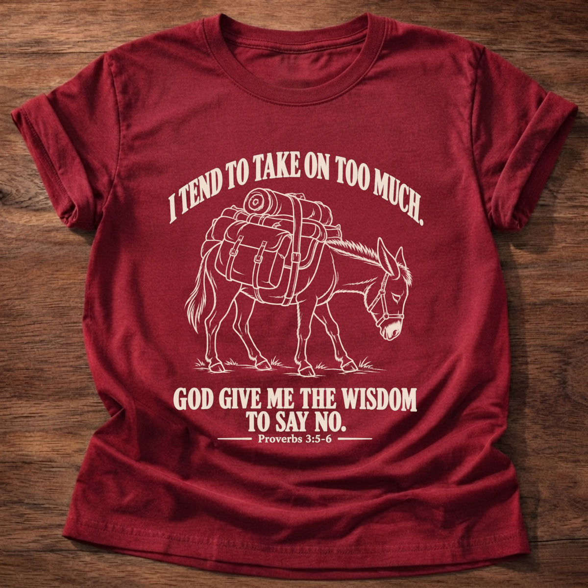 Cherry Red t-shirt printed with a pack donkey weighed down with overstuffed bags and bundles graphic and “I tend to take on too much. God give me the wisdom to say no.” Proverbs 3:5-6 faith based gift
