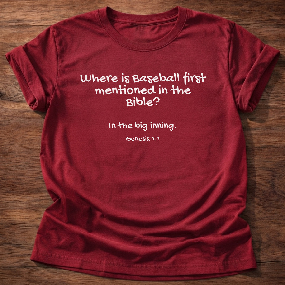 Cherry Red t-shirt printed with a simple hand-lettered Bible joke graphic and “Where is baseball first mentioned in the Bible? In the big inning.” Genesis 1:1 Christian shirt