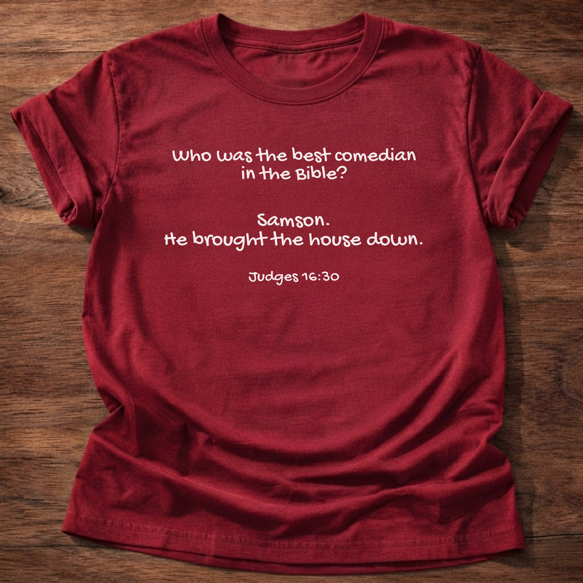 Cherry Red t-shirt printed with a simple hand-lettered Bible joke graphic and “Who was the best comedian in the Bible? Samson. He brought the house down.” Judges 16:30 Christian shirt
