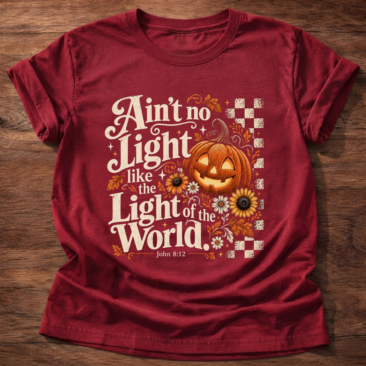 Cherry Red t-shirt printed with a retro glowing jack-o'-lantern with sunflowers and checkerboard graphic and “Ain't no light like the Light of the World.” John 8:12 Christian shirt