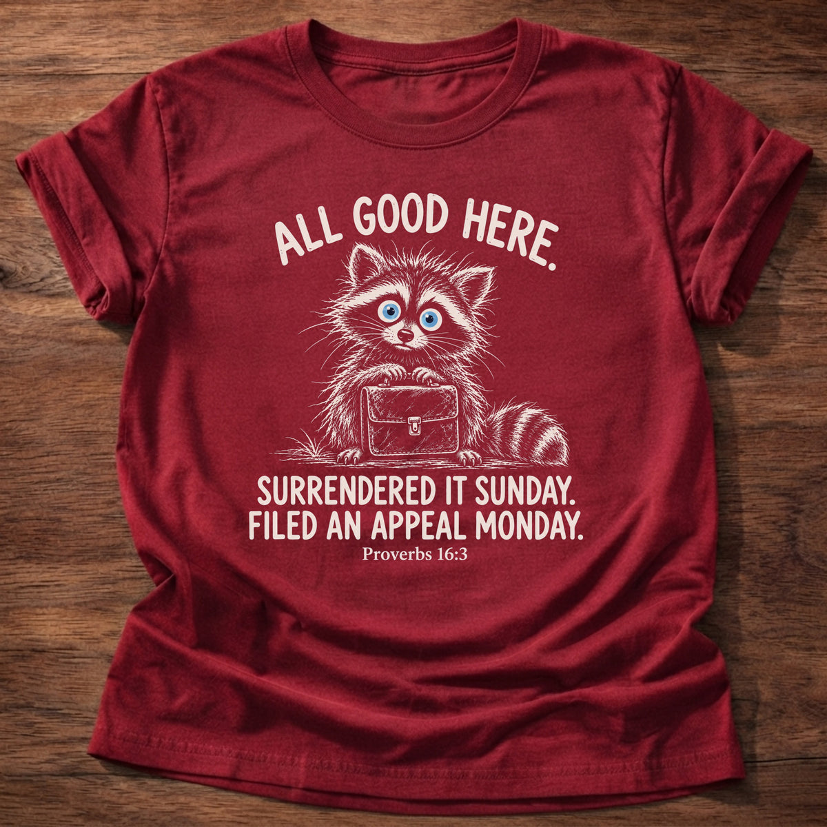 Cherry Red t-shirt printed with a raccoon carrying a briefcase graphic and “All good here. Surrendered it Sunday. Filed an appeal Monday.” Proverbs 16:3 Christian shirt