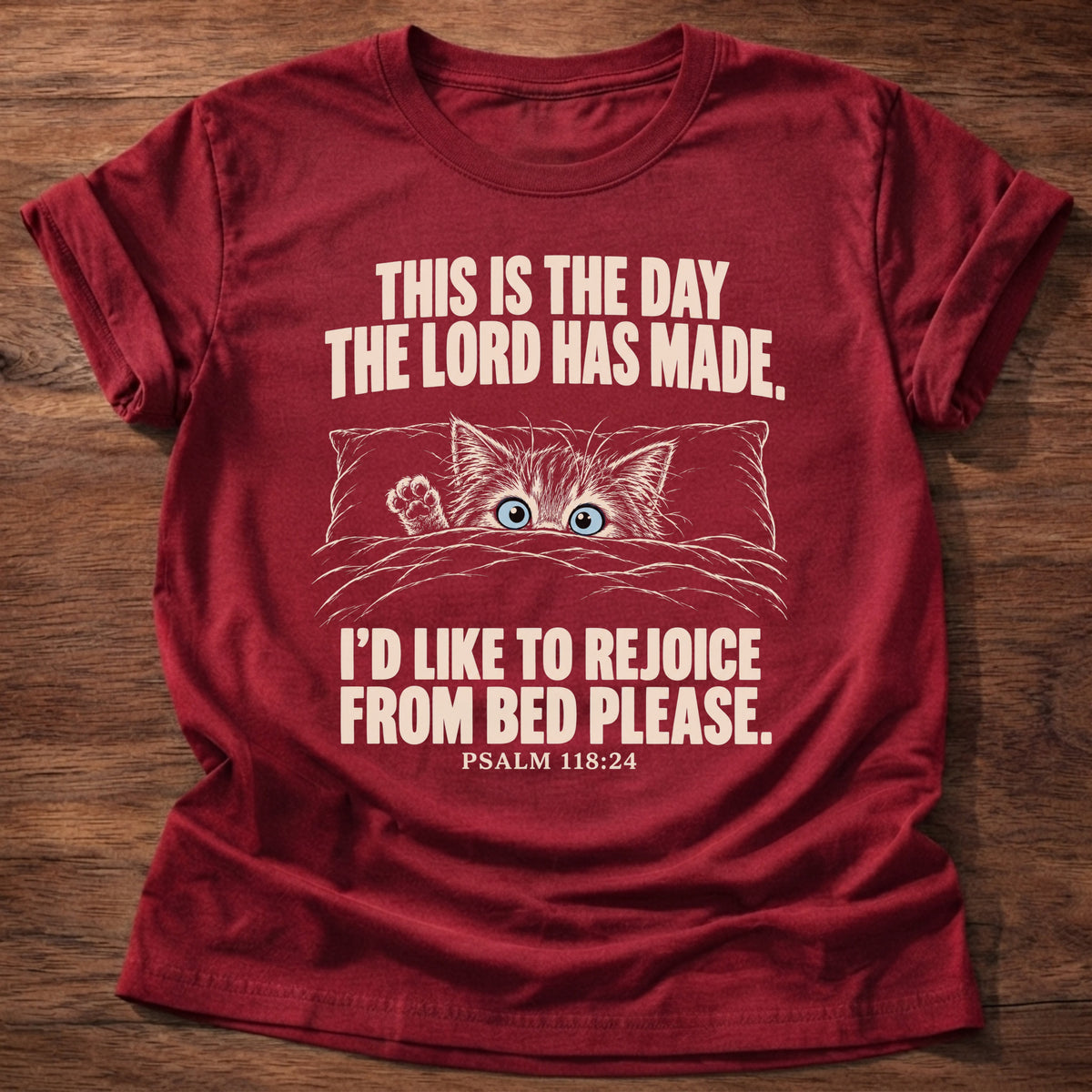 Rejoicing From Bed T-Shirt in Cherry Red featuring a sleepy cat peeking over the bed covers and Psalm 118:24 tired morning humor design