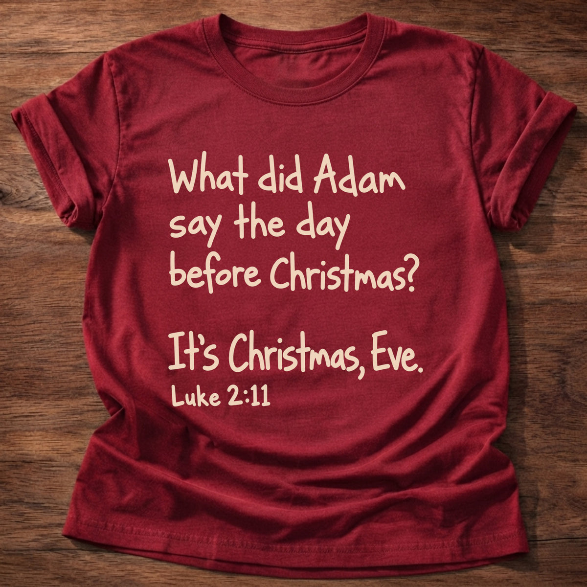 Cherry Red t-shirt printed with a simple hand-lettered Bible joke graphic and “What did Adam say the day before Christmas? It's Christmas, Eve.” Luke 2:11 Christian shirt