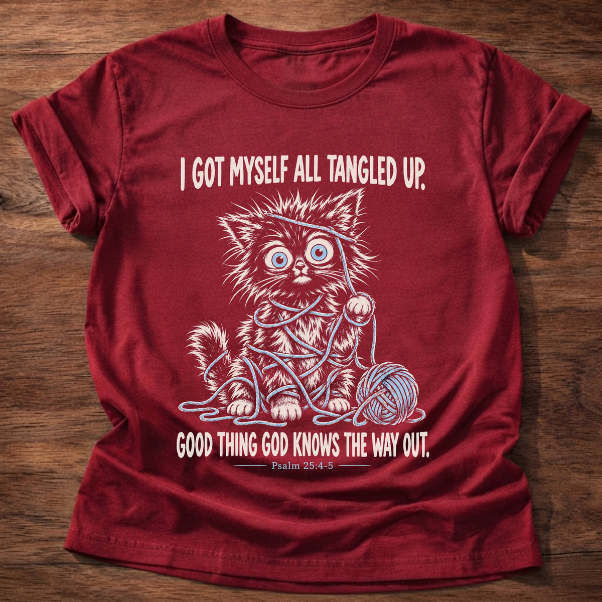 Cherry Red t-shirt printed with a wide-eyed kitten tangled up in blue yarn next to a yarn ball graphic and “I got myself all tangled up. Good thing God knows the way out.” Psalm 25:4-5 faith based gift