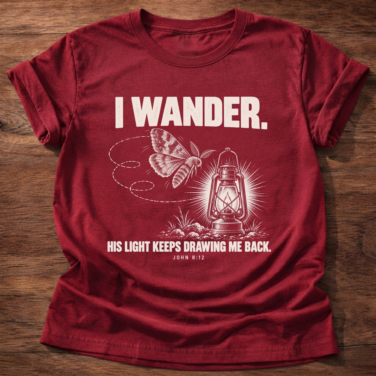 Cherry Red t-shirt printed with a moth circling a glowing lantern graphic and 'I wander. His light keeps drawing me back.' John 8:12 faith based gift