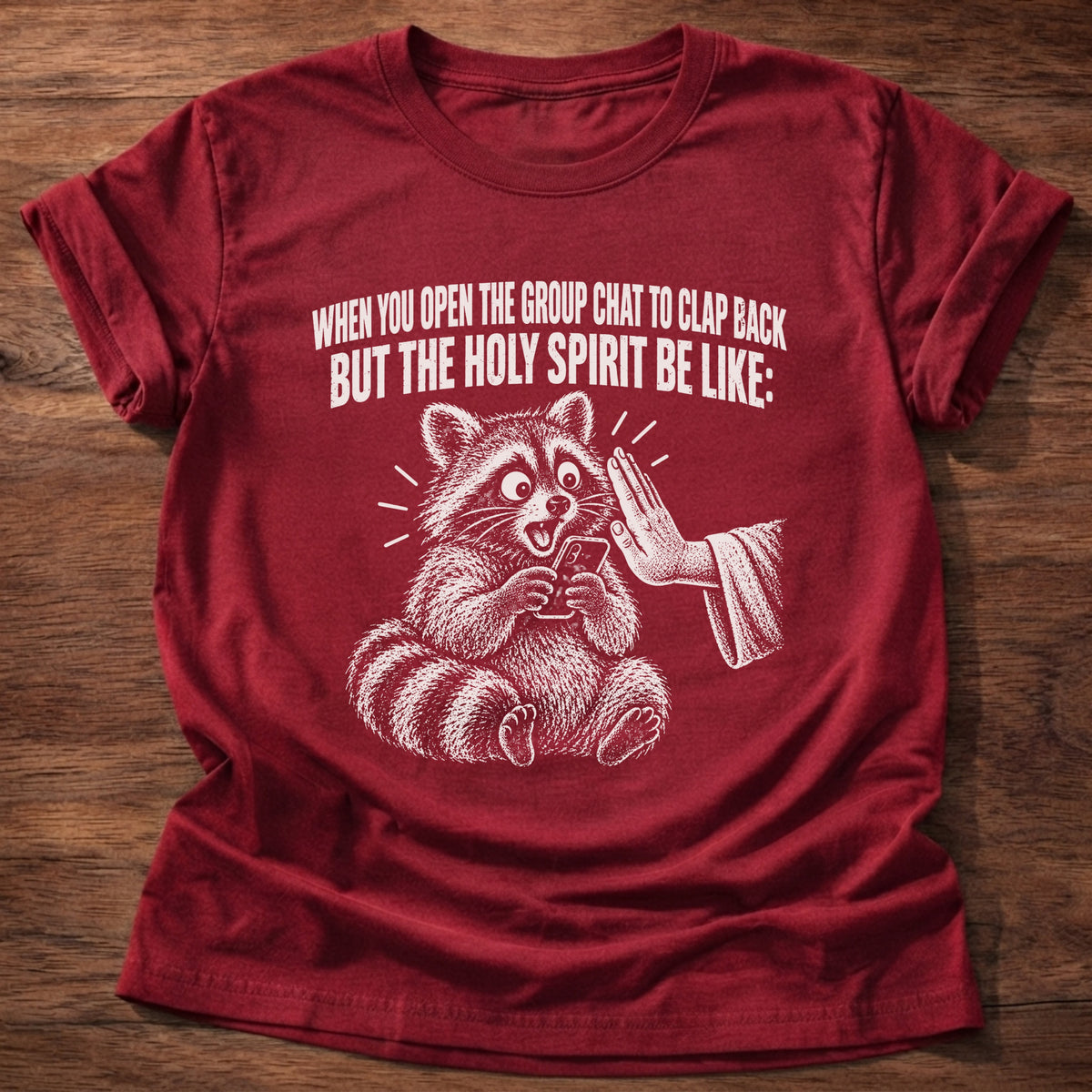 Cherry Red t-shirt printed with a raccoon covering its own mouth graphic and 'When you open the group chat to clap back but the Holy Spirit be like.' Proverbs 21:23 faith based gift
