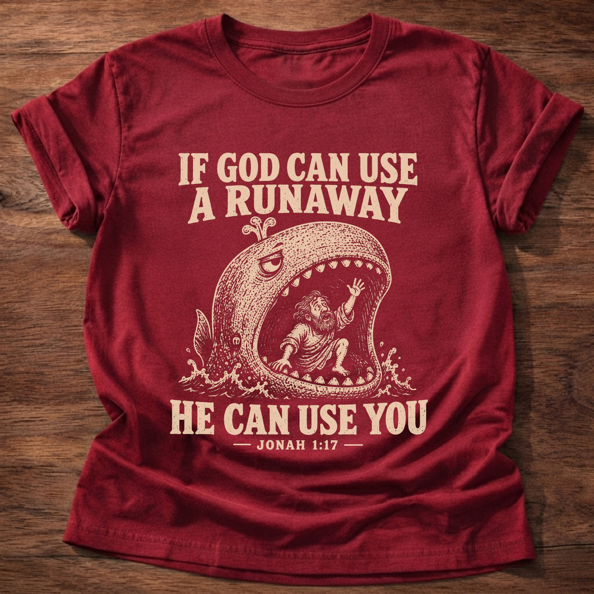 Cherry Red t-shirt printed with a whale swallowing a runaway figure and 'If God can use a runaway, He can use you.' Jonah 1:17 faith based gift