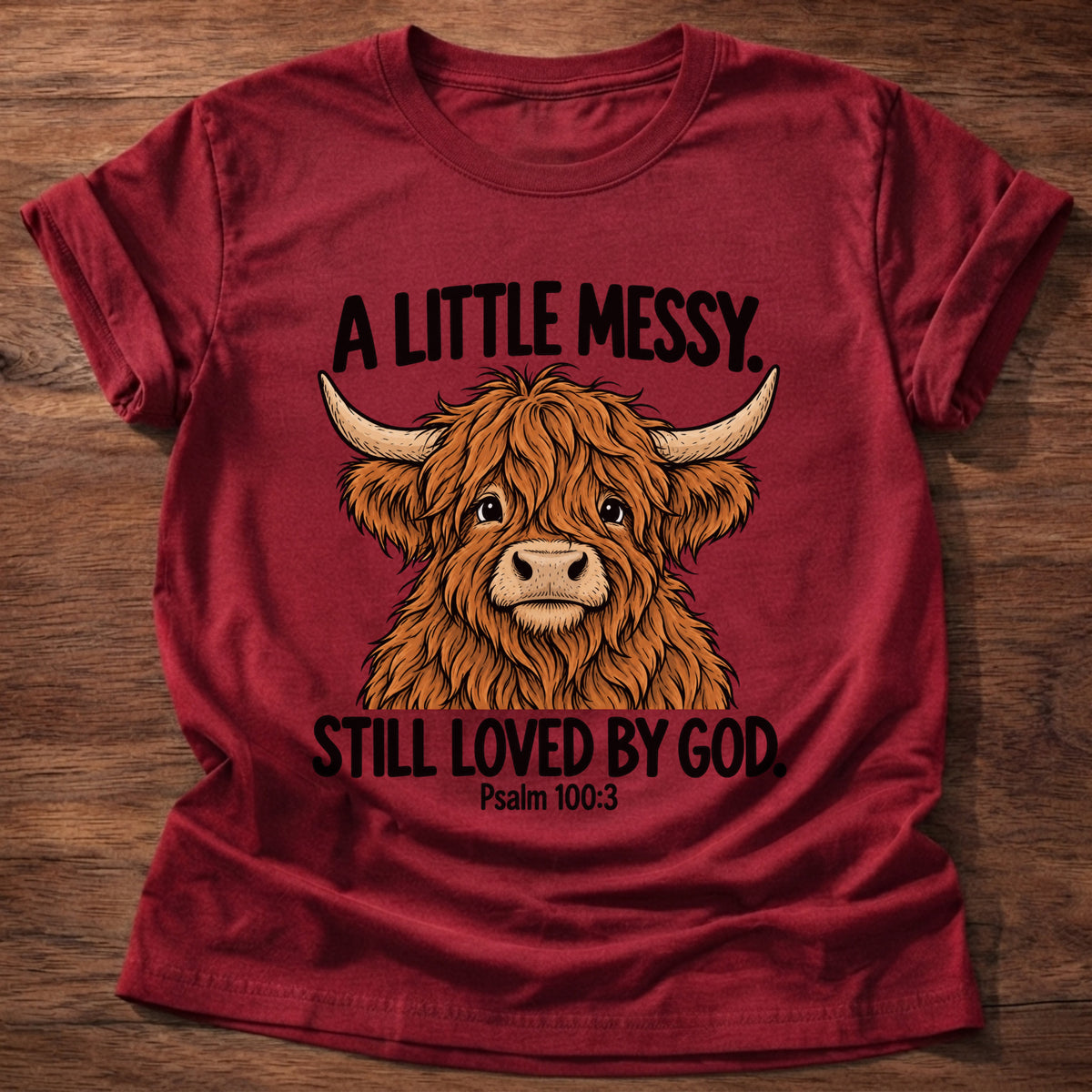 Cherry Red t-shirt printed with a highland cow graphic and 'A little messy. Still loved by God.' Psalm 100:3 faith based gift