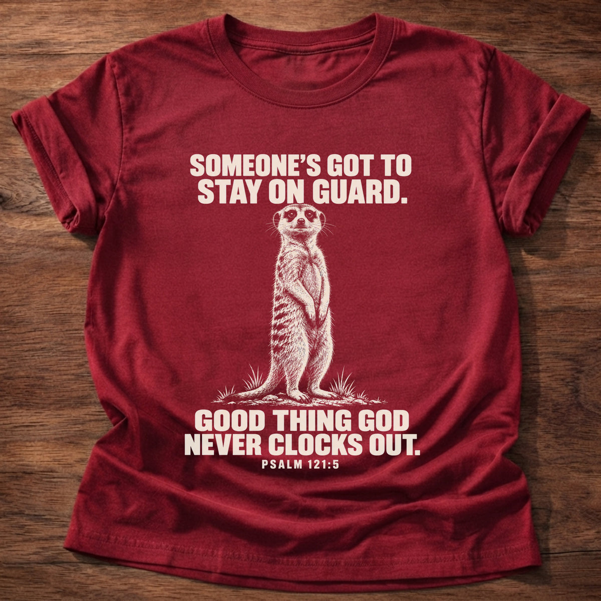 Cherry Red t-shirt printed with a meerkat standing guard on lookout graphic and 'Someone's got to stay on guard. Good thing God never clocks out.' Psalm 121:5 faith based gift
