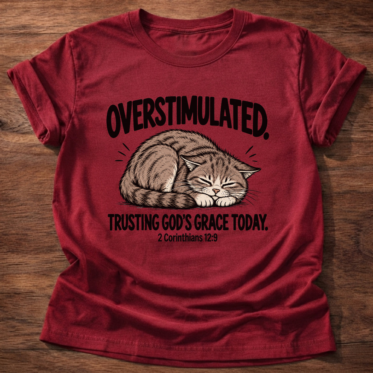 Cherry Red t-shirt printed with a cat curled asleep graphic and 'Overstimulated. Trusting God's grace today.' 2 Corinthians 12:9 faith based gift