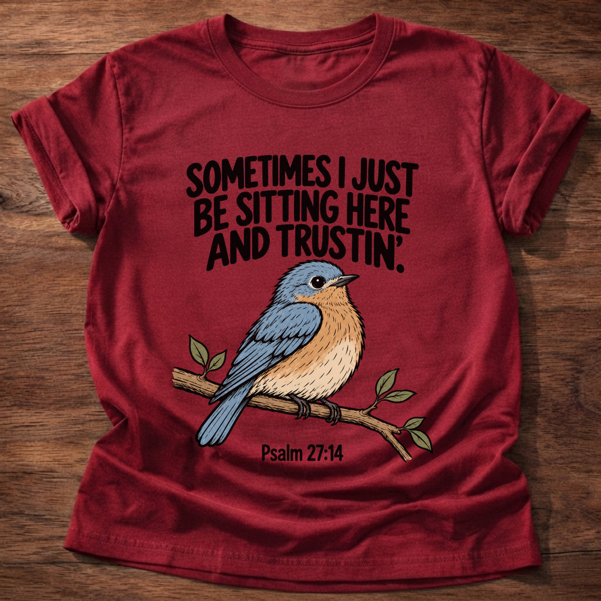 Cherry Red t-shirt printed with a bluebird on a branch graphic and 'Sometimes I just be sitting here and trustin'.' Psalm 27:14 faith based gift