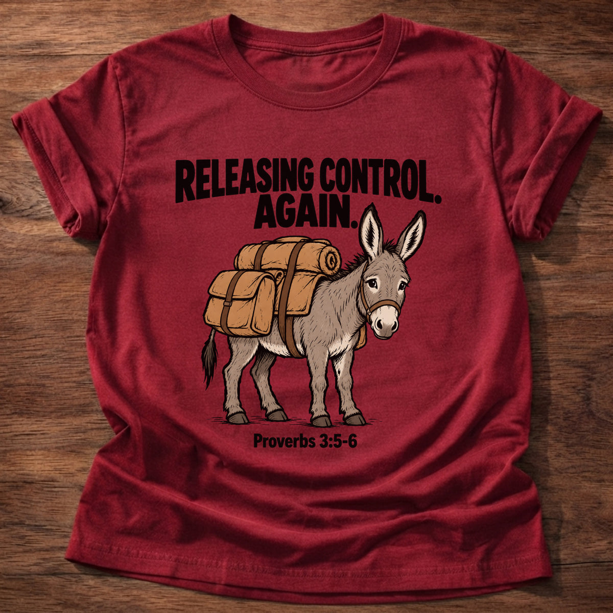Cherry Red t-shirt printed with a donkey carrying a backpack graphic and 'Releasing control. Again.' Proverbs 3:5-6 faith based gift