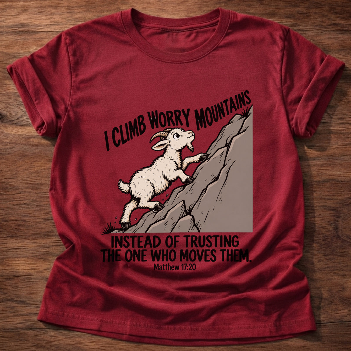 Cherry Red t-shirt printed with a goat climbing a mountain graphic and 'I climb worry mountains instead of trusting the One who moves them.' Matthew 17:20 faith based gift