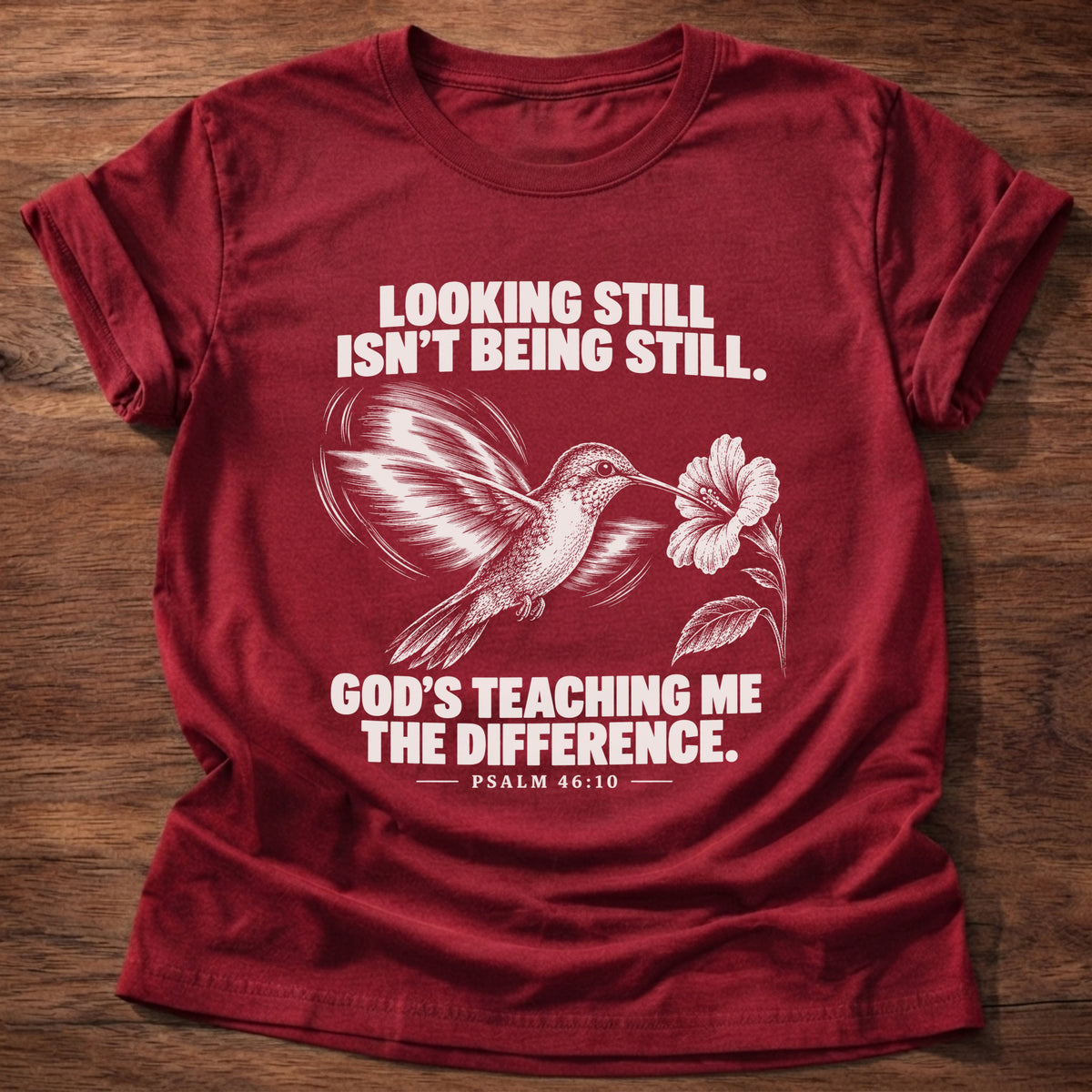 Cherry Red t-shirt printed with a hummingbird hovering beside a flower graphic and 'Looking still isn't being still. God's teaching me the difference.' Psalm 46:10 faith based gift