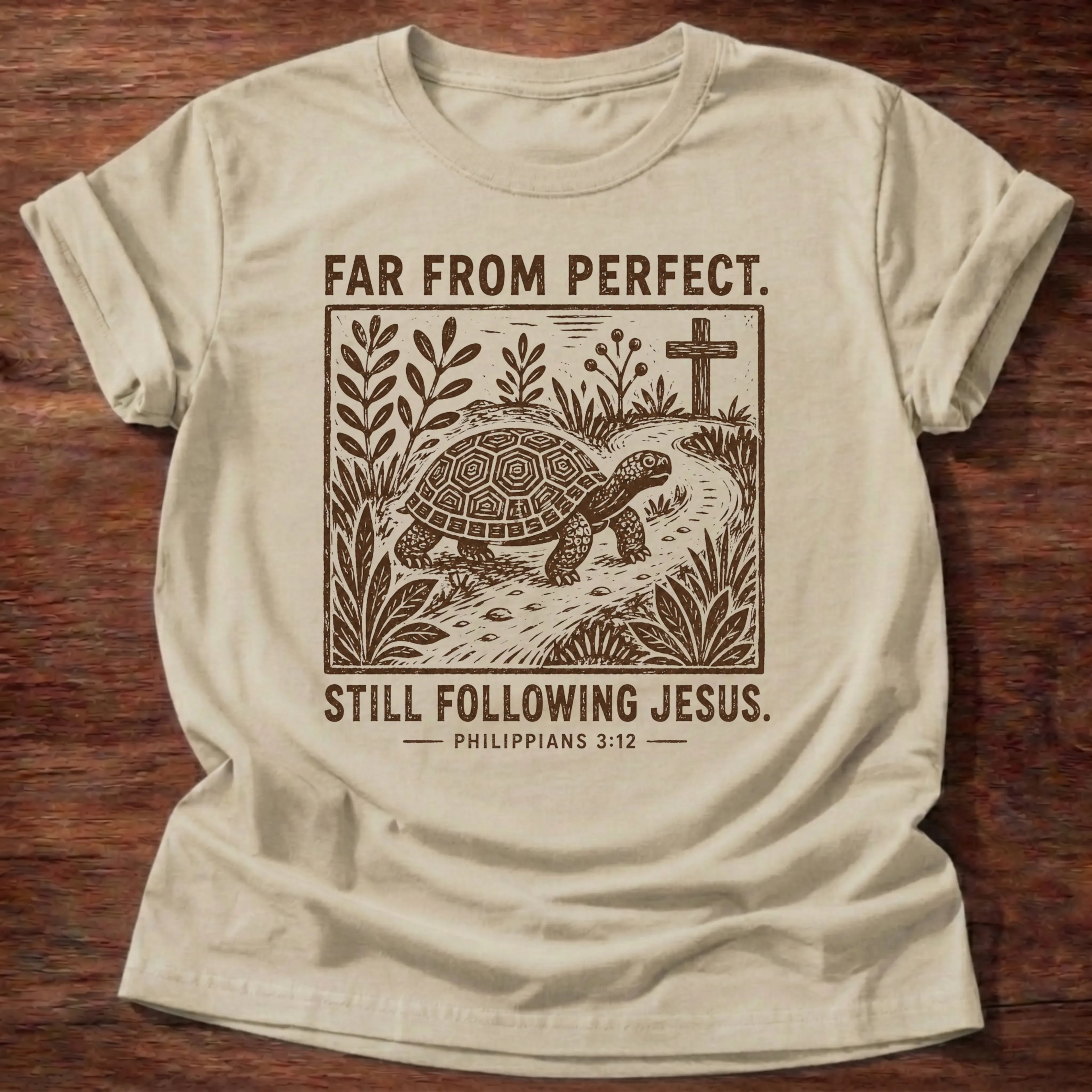 Sand Gildan 64000 t-shirt with a turtle and cross illustration and 'Far From Perfect, Still Following Jesus' text, Philippians 3:12 Christian t-shirt