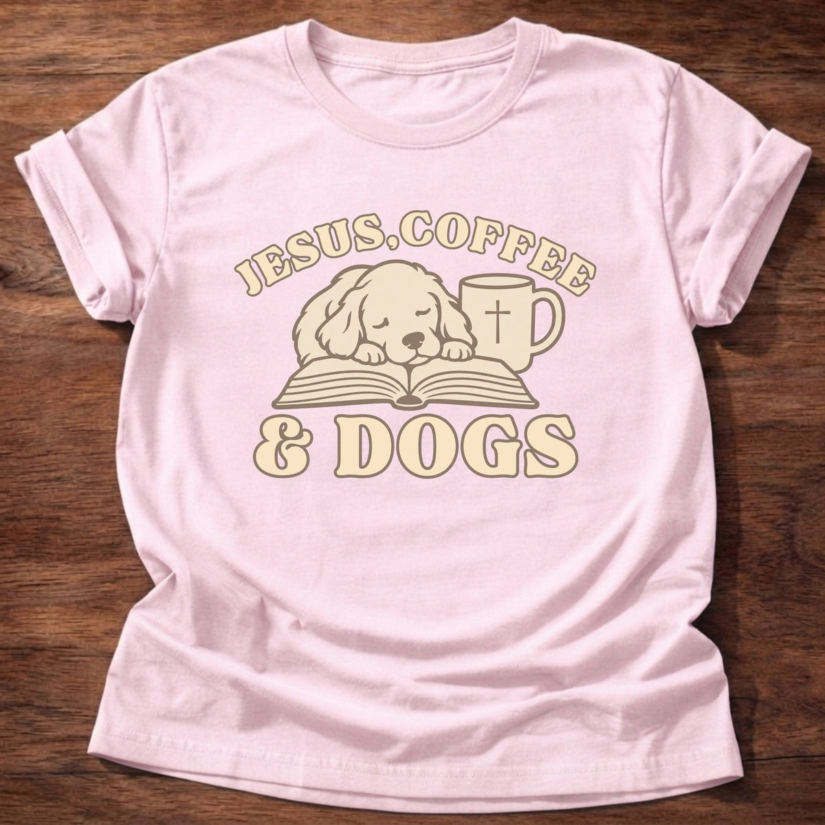 Light Pink t-shirt printed with a sleepy puppy resting on an open Bible beside a coffee mug with a cross and “Jesus, Coffee & Dogs” Christian shirt