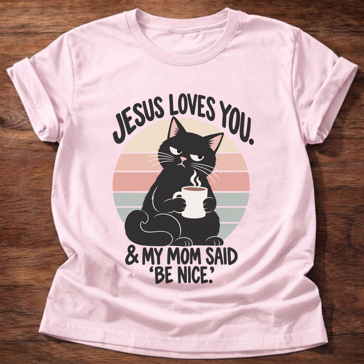 Light Pink t-shirt printed with a grumpy black cat holding a steaming coffee mug in front of a retro striped sunset graphic and “Jesus loves you. & my mom said 'be nice.'” faith based gift