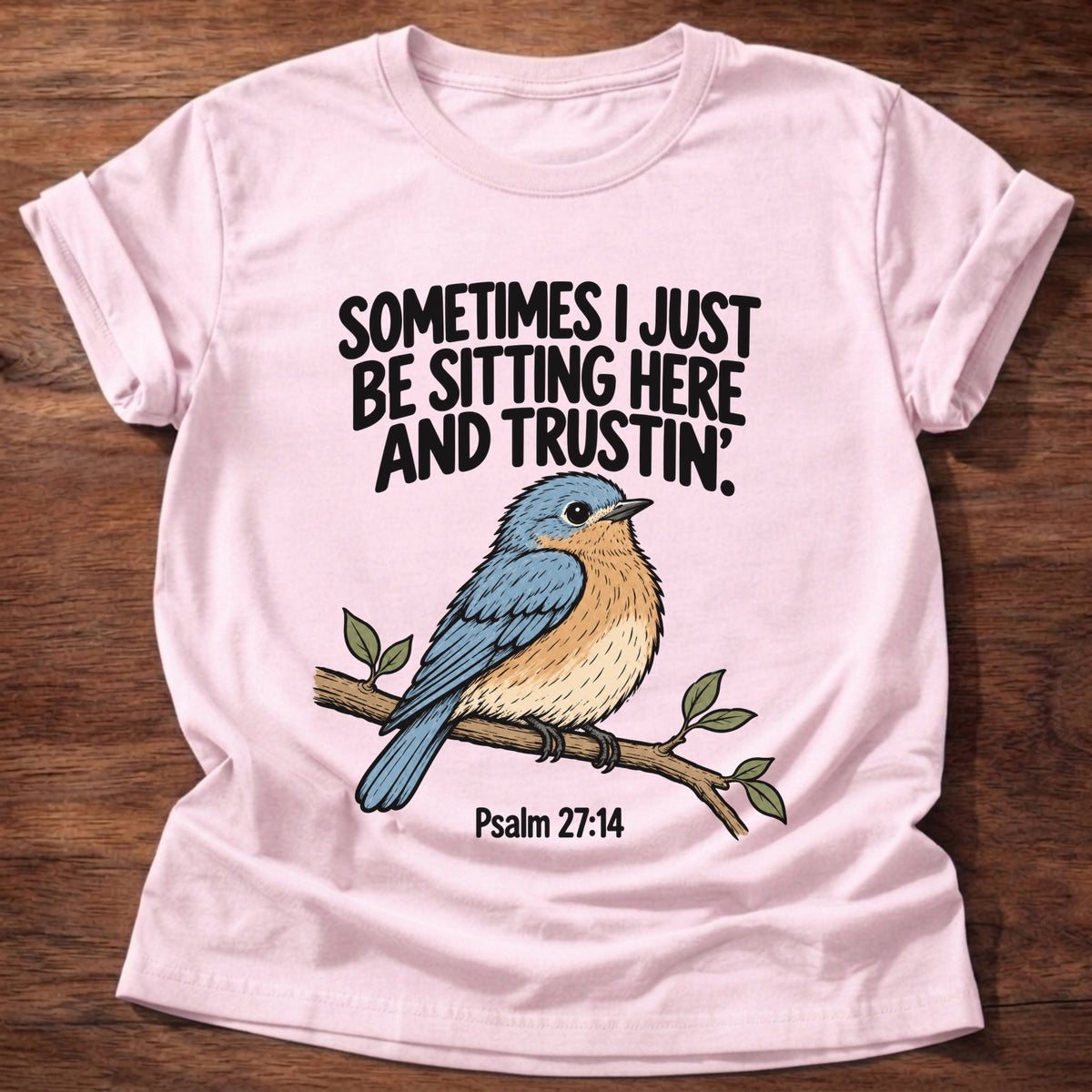 Light Pink t-shirt printed with a bluebird on a branch graphic and 'Sometimes I just be sitting here and trustin'.' Psalm 27:14 faith based gift