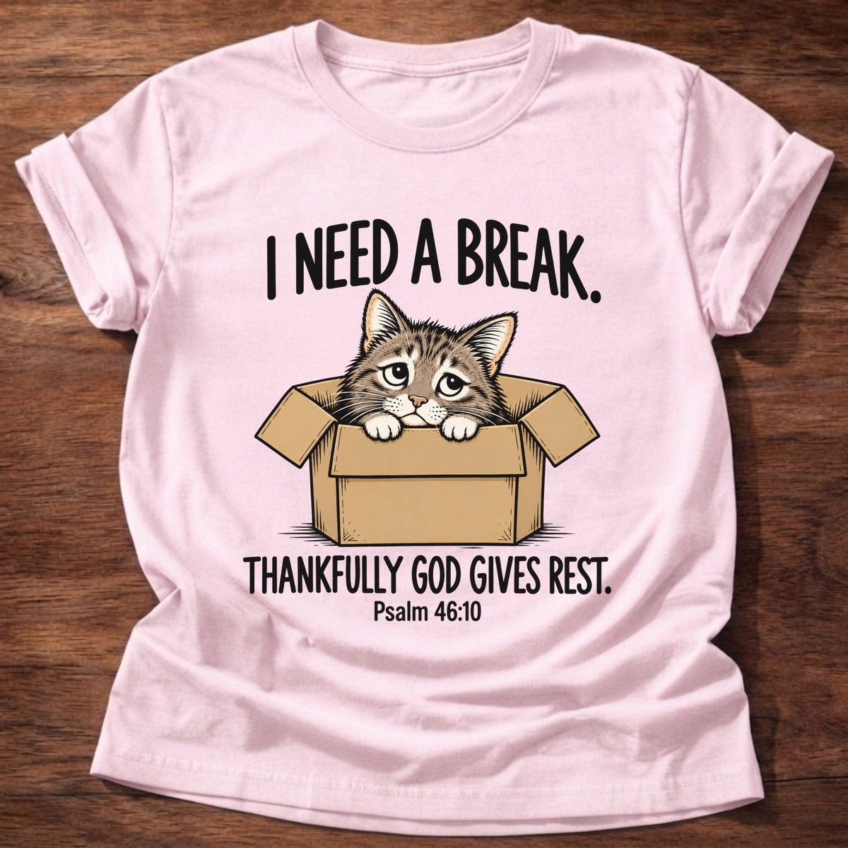 Light Pink t-shirt printed with a cat curled in a cardboard box graphic and 'I need a break. Thankfully God gives rest.' Psalm 46:10 faith based gift