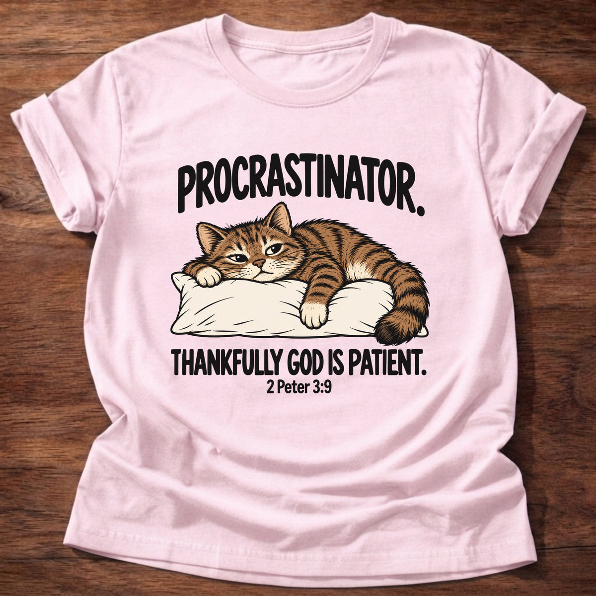 Light Pink t-shirt printed with a cat sleeping on a pillow graphic and 'Procrastinator. Thankfully God is patient.' 2 Peter 3:9 faith based gift
