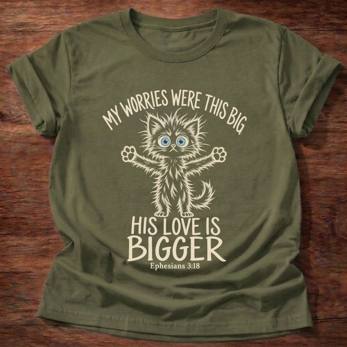 Military Green t-shirt printed with a wide-eyed fluffy kitten stretching its arms wide graphic and “My worries were this big. His love is bigger.” Ephesians 3:18 Christian shirt