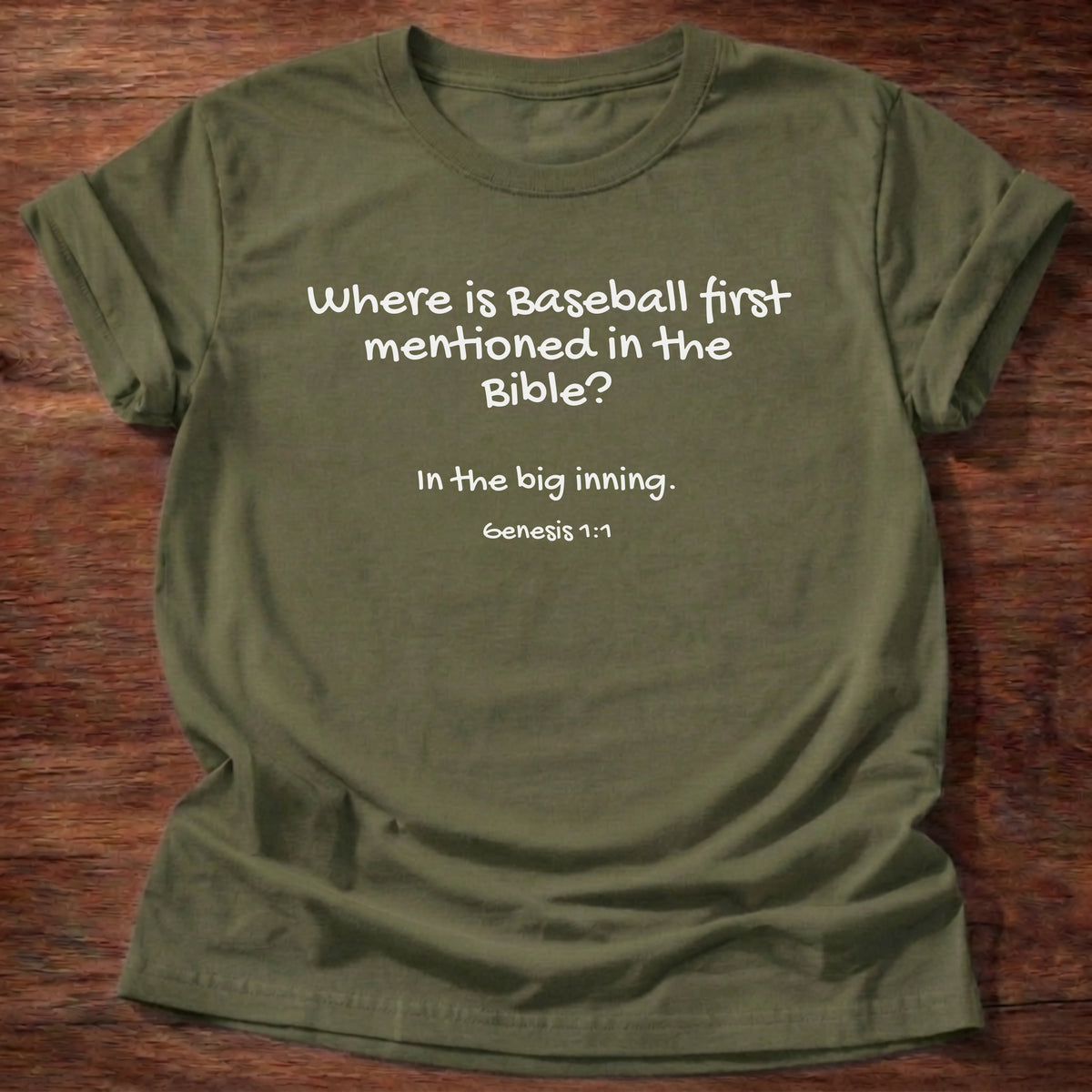 Military Green t-shirt printed with a simple hand-lettered Bible joke graphic and “Where is baseball first mentioned in the Bible? In the big inning.” Genesis 1:1 Christian shirt