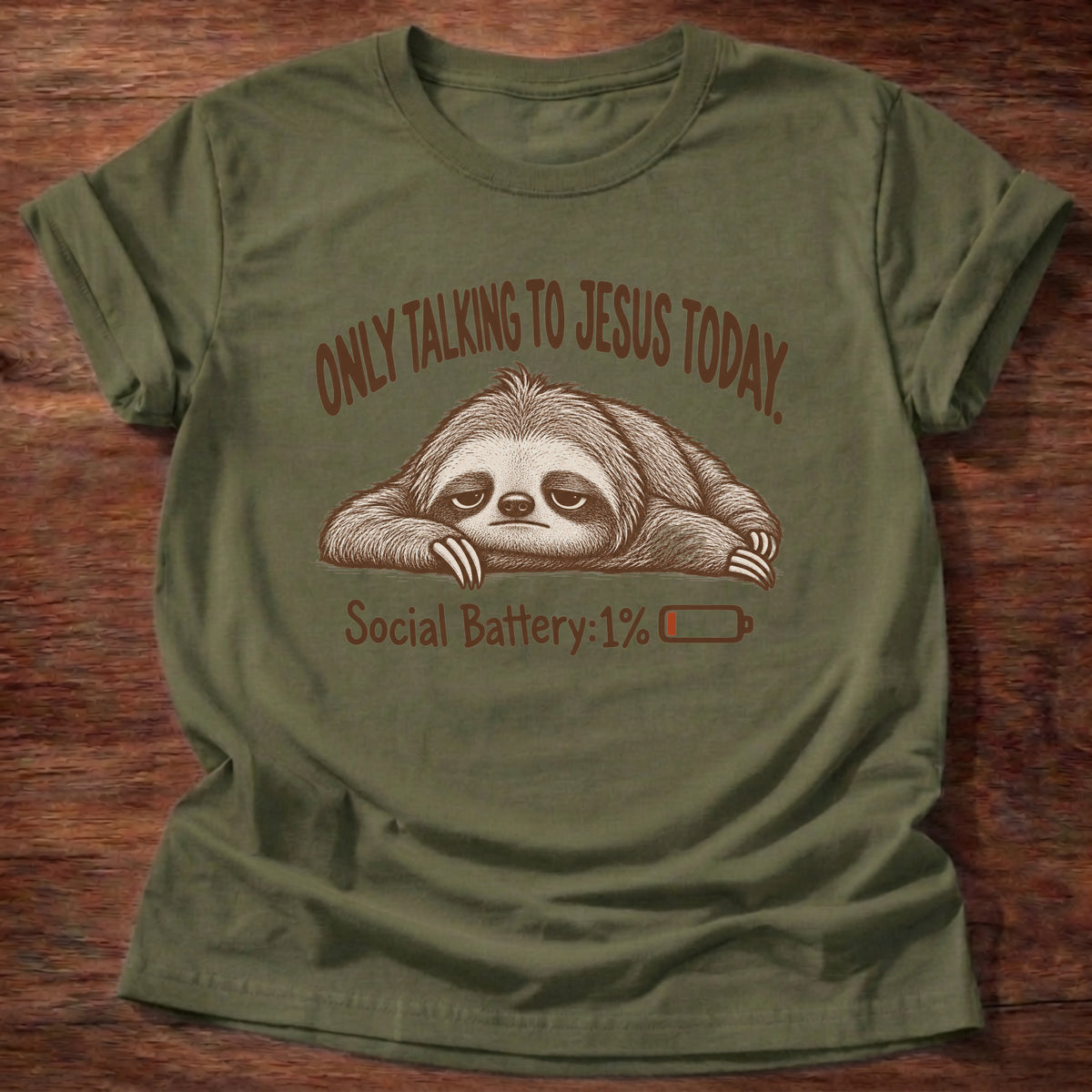 Military Green t-shirt printed with an exhausted sloth lying flat next to a nearly empty battery icon graphic and “Only talking to Jesus today. Social Battery: 1%” faith based gift