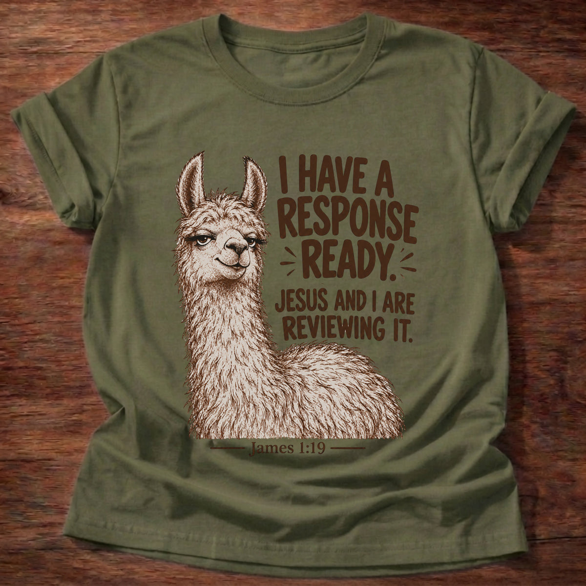 Military Green t-shirt printed with a side-eyeing llama with a knowing smirk graphic and “I have a response ready. Jesus and I are reviewing it.” James 1:19 faith based gift