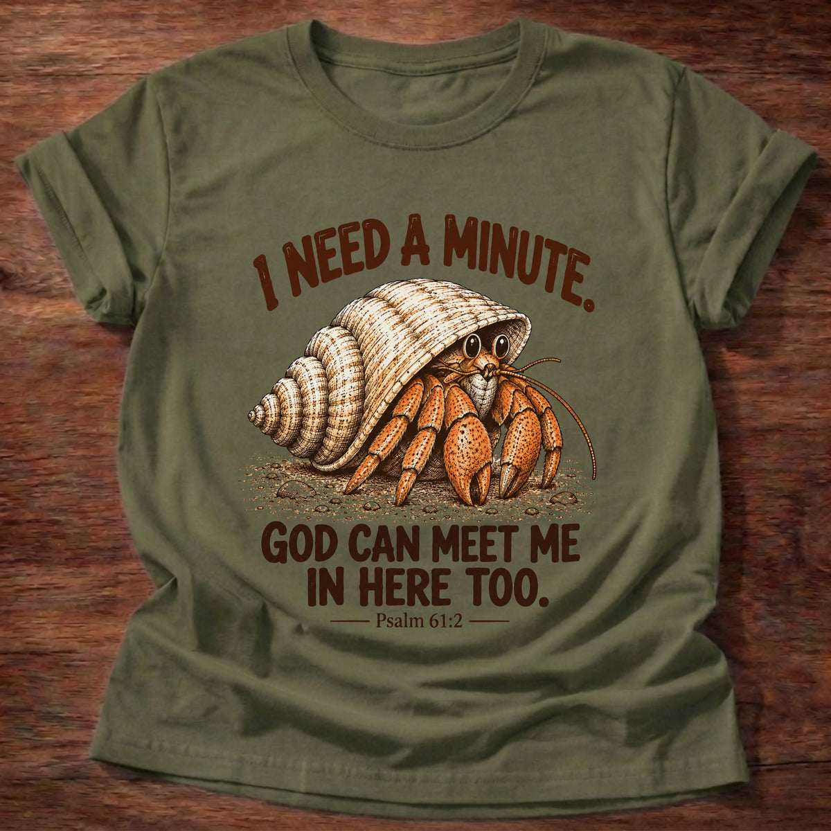 Military Green t-shirt printed with a hermit crab peeking out of its spiral shell graphic and “I need a minute. God can meet me in here too.” Psalm 61:2 faith based gift