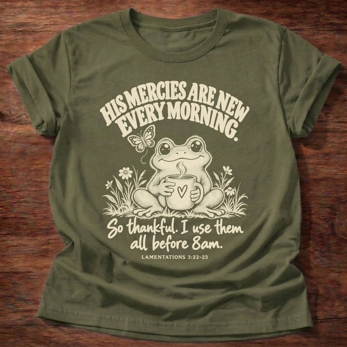 Mercies Every Morning T-Shirt in Military Green featuring a smiling frog holding a coffee mug among wildflowers and Lamentations 3:22-23 coffee and grace humor design
