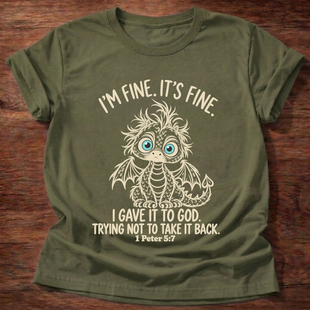 Military Green t-shirt printed with a wide-eyed, frazzled baby dragon graphic and “I'm fine. It's fine. I gave it to God. Trying not to take it back.” 1 Peter 5:7 Christian shirt