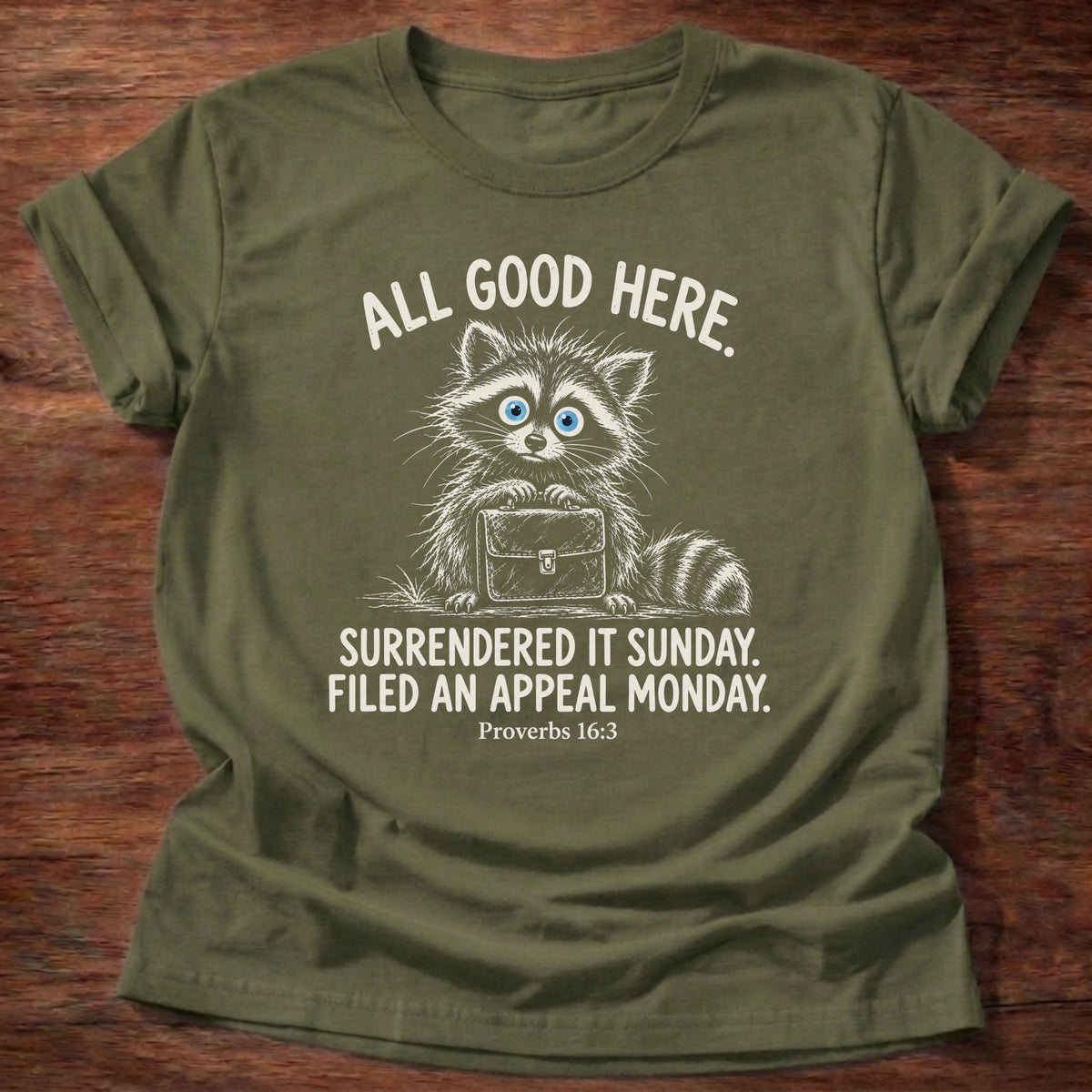 Military Green t-shirt printed with a raccoon carrying a briefcase graphic and “All good here. Surrendered it Sunday. Filed an appeal Monday.” Proverbs 16:3 Christian shirt