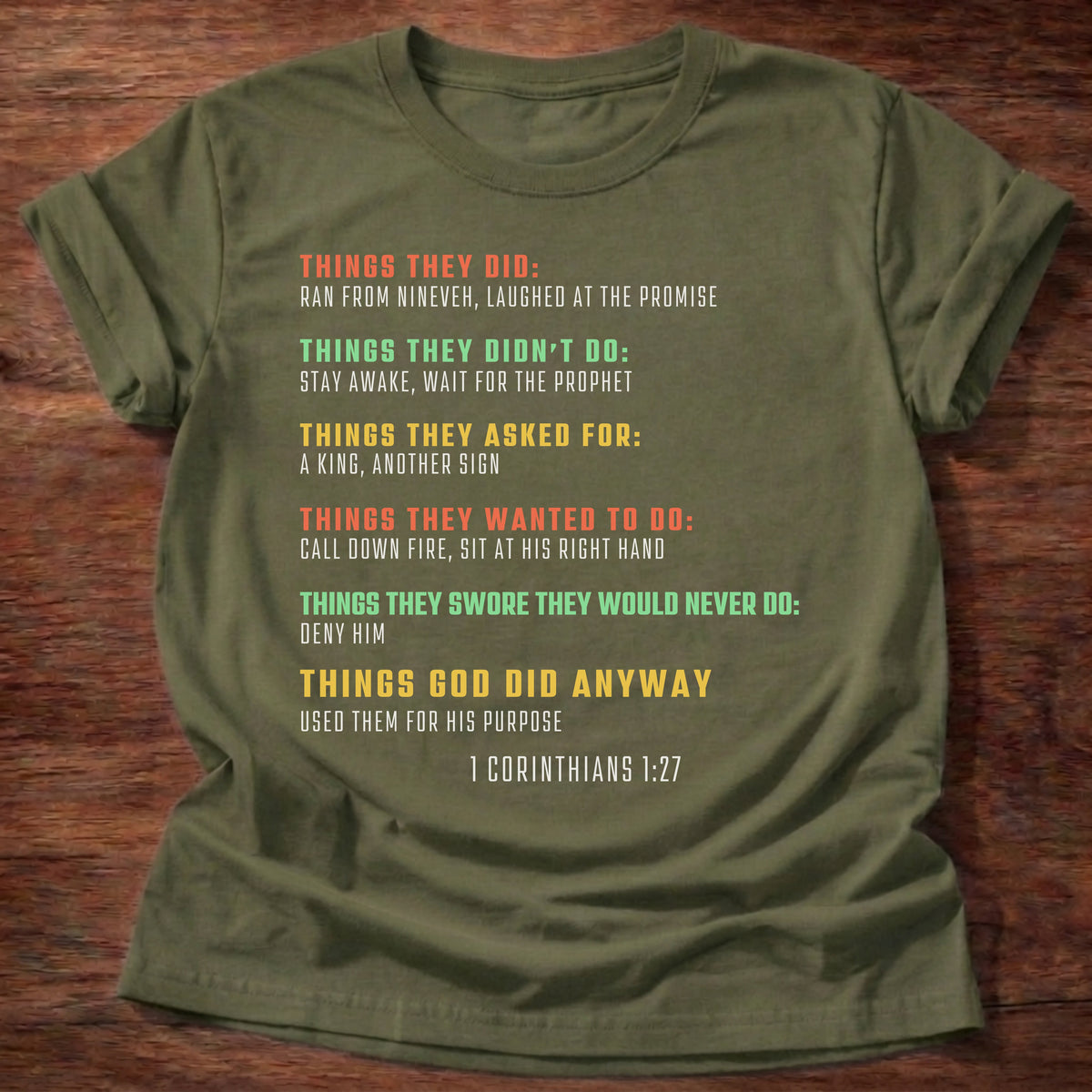 Military Green t-shirt printed with bold colorful typography listing what Bible heroes did graphic and “Things they did. Things God did anyway.” 1 Corinthians 1:27 Christian shirt