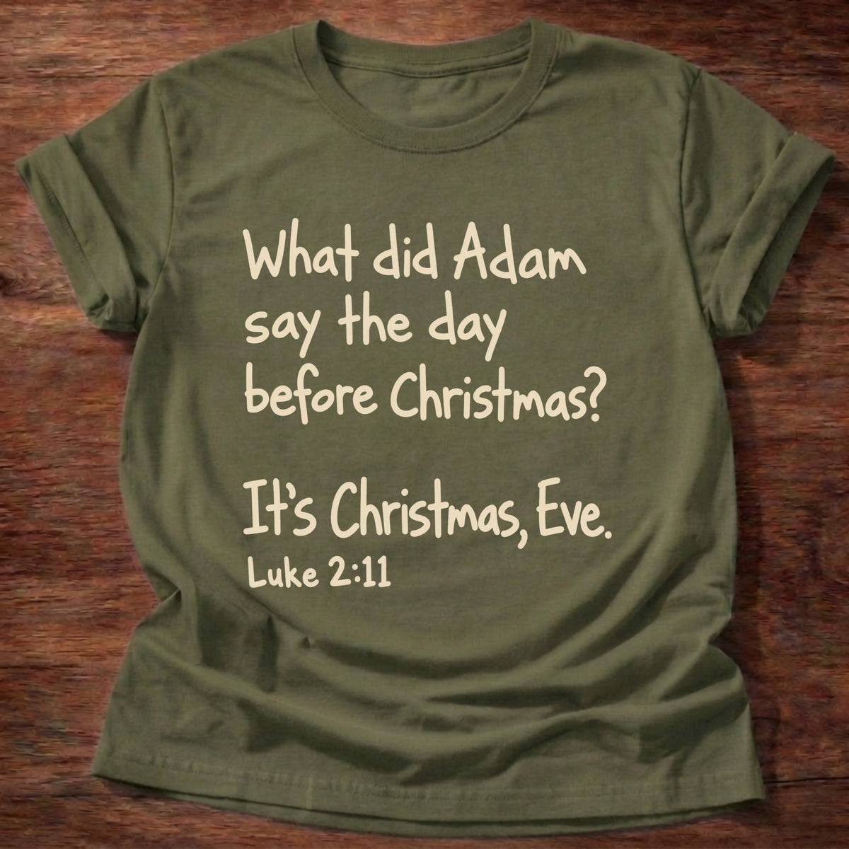 Military Green t-shirt printed with a simple hand-lettered Bible joke graphic and “What did Adam say the day before Christmas? It's Christmas, Eve.” Luke 2:11 Christian shirt