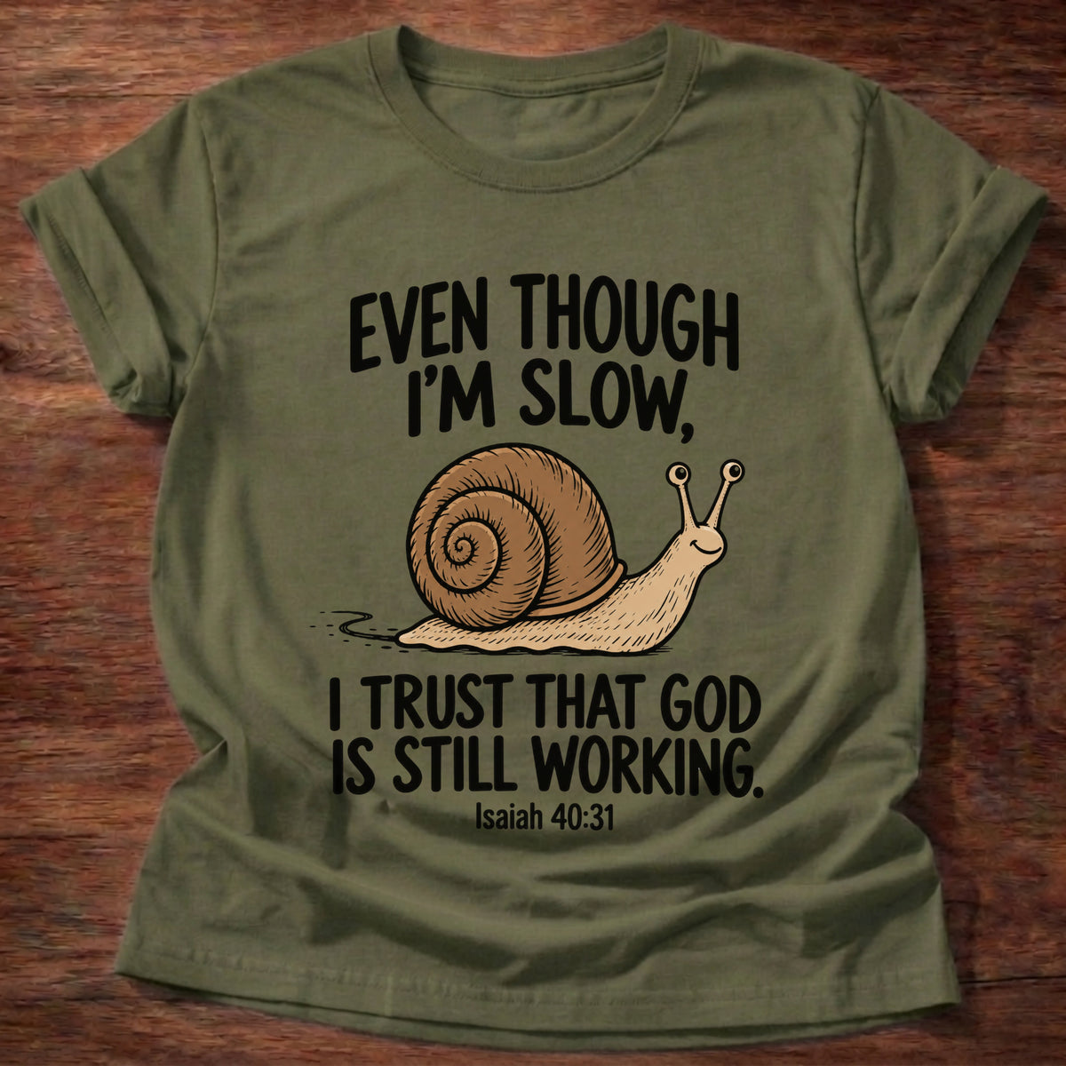 Military Green t-shirt printed with a snail graphic and 'Even though I'm slow. I trust that God is still working.' Isaiah 40:31 faith based gift