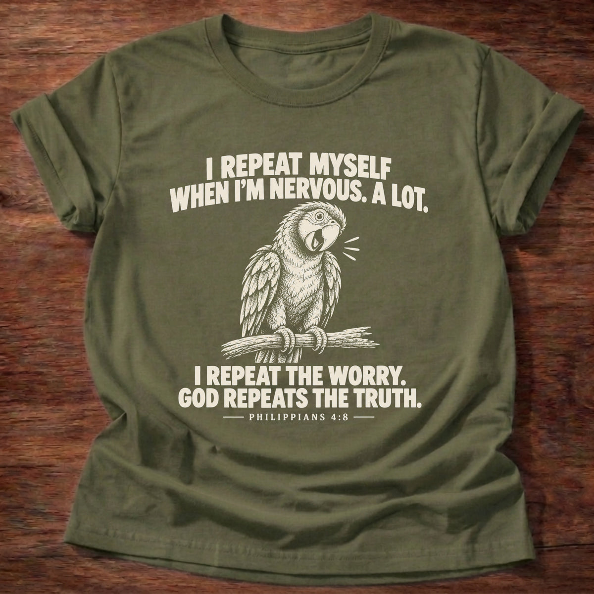 Military Green t-shirt printed with a parrot squawking on a perch graphic and 'I repeat myself when I'm nervous. A lot. I repeat the worry. God repeats the truth.' Philippians 4:6 faith based gift