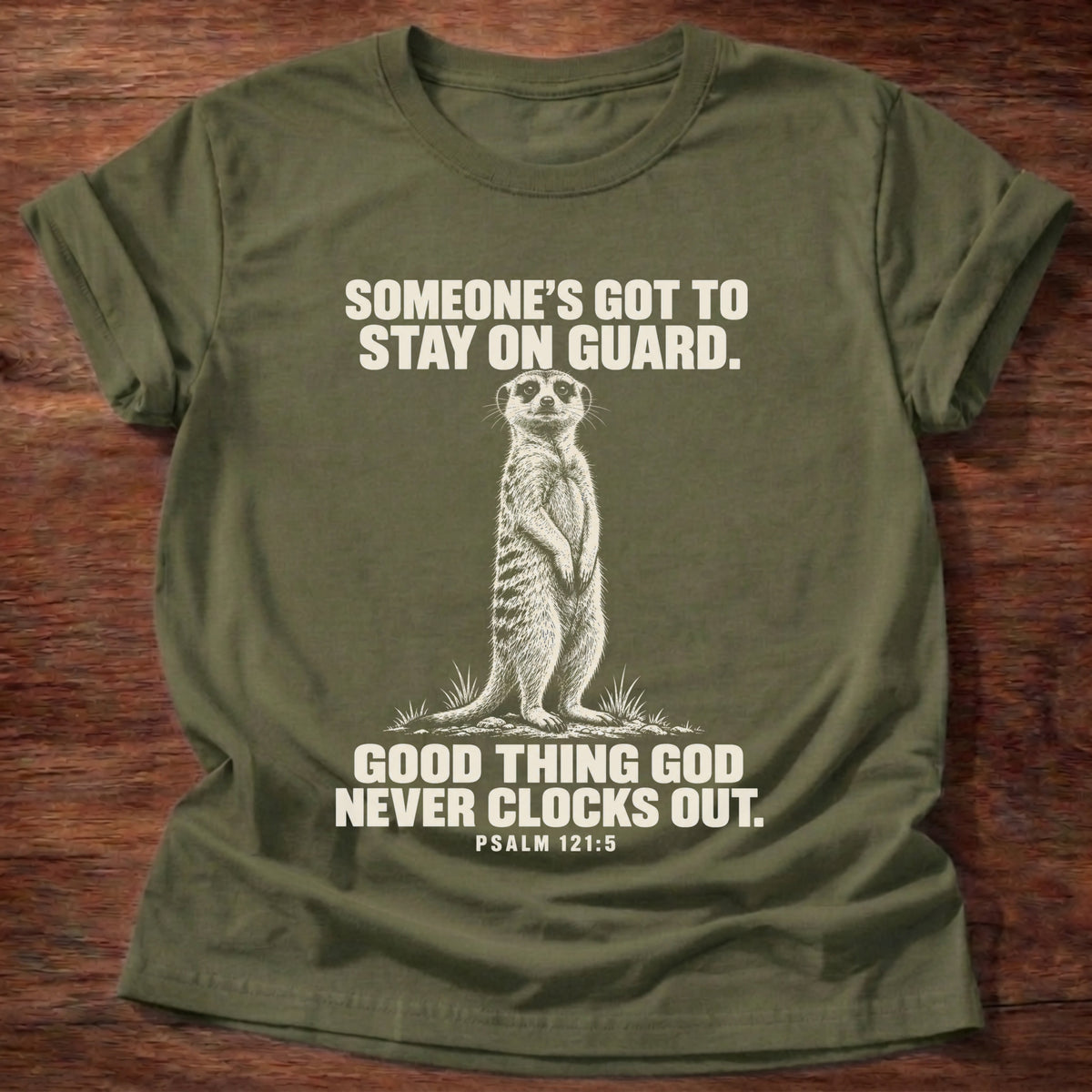 Military Green t-shirt printed with a meerkat standing guard on lookout graphic and 'Someone's got to stay on guard. Good thing God never clocks out.' Psalm 121:5 faith based gift