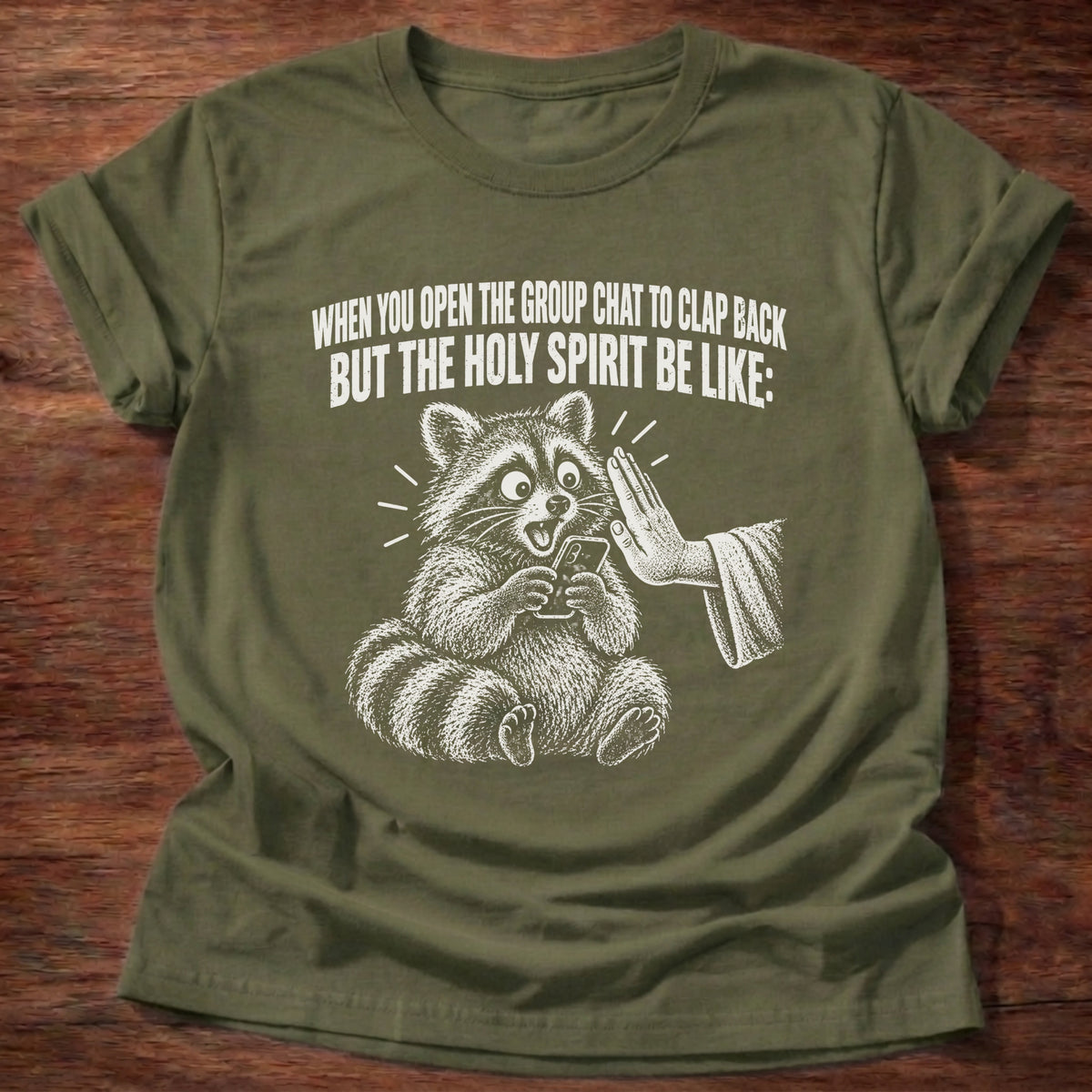 Military Green t-shirt printed with a raccoon covering its own mouth graphic and 'When you open the group chat to clap back but the Holy Spirit be like.' Proverbs 21:23 faith based gift
