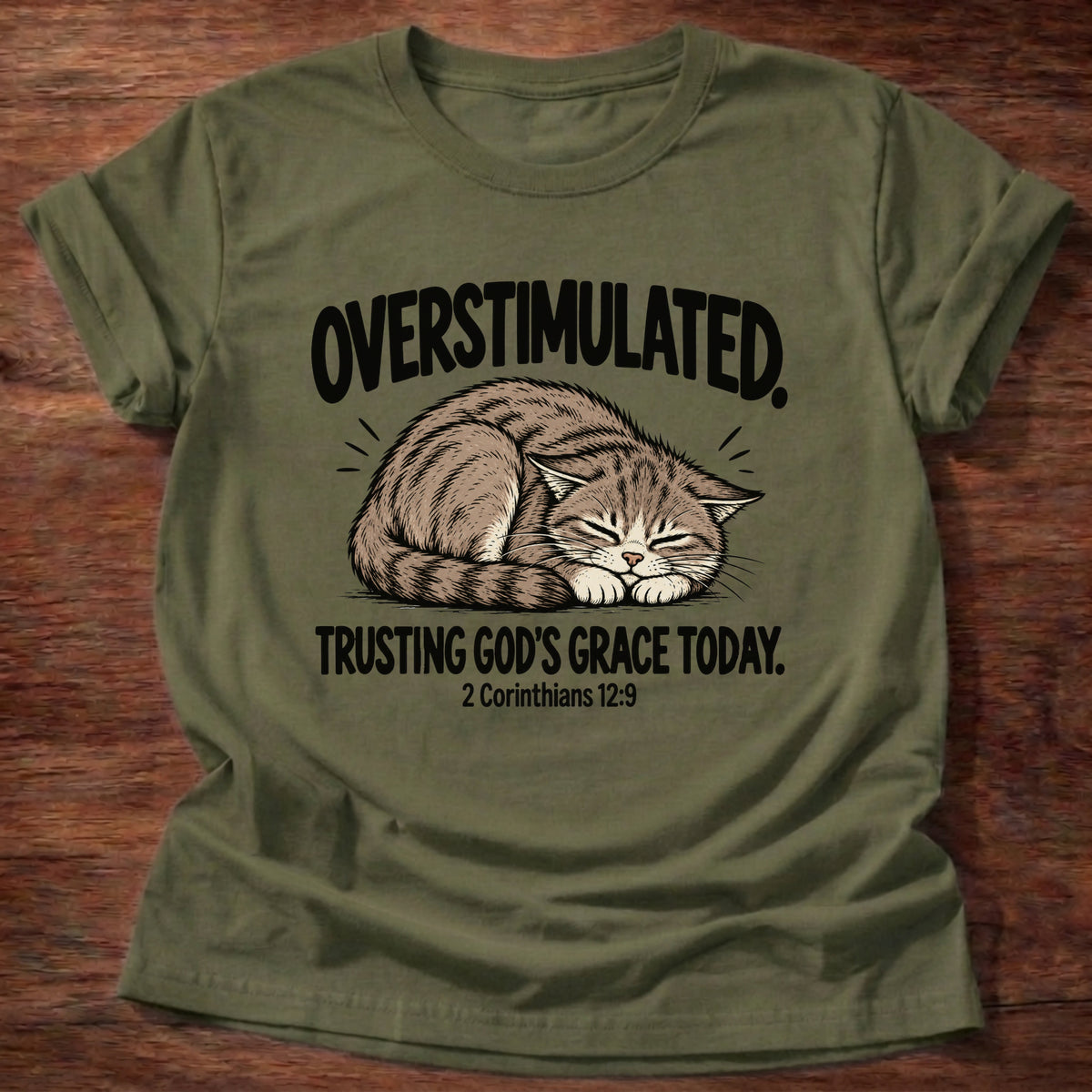 Military Green t-shirt printed with a cat curled asleep graphic and 'Overstimulated. Trusting God's grace today.' 2 Corinthians 12:9 faith based gift