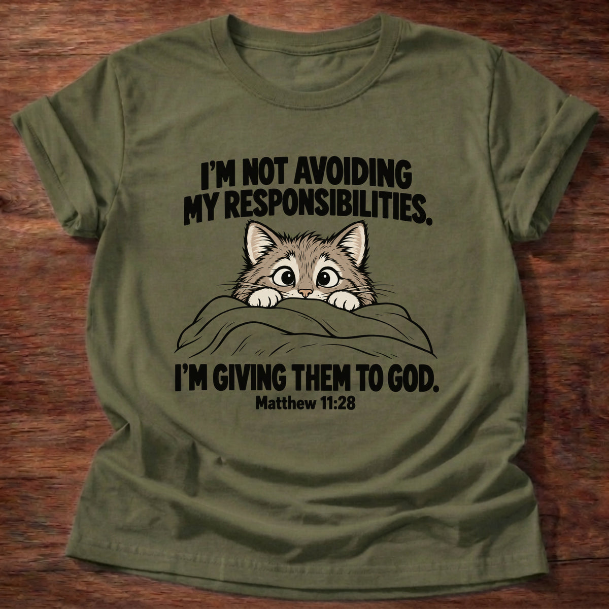 Military Green t-shirt printed with a cat peeking over a blanket graphic and 'I'm not avoiding my responsibilities. I'm giving them to God.' Matthew 11:28 faith based gift