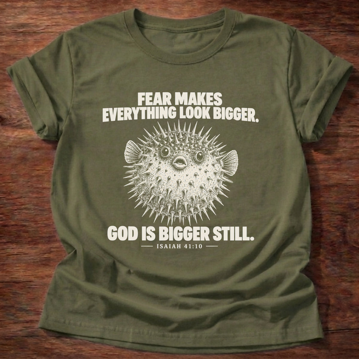 Military Green t-shirt printed with a pufferfish inflated to look bigger graphic and 'Fear makes everything look bigger. God is bigger still.' Isaiah 41:10 faith based gift