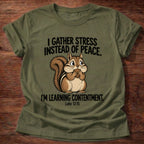 Military Green t-shirt printed with a squirrel gathering acorns graphic and 'I gather stress instead of peace. I'm learning contentment.' Luke 12:15 faith based gift