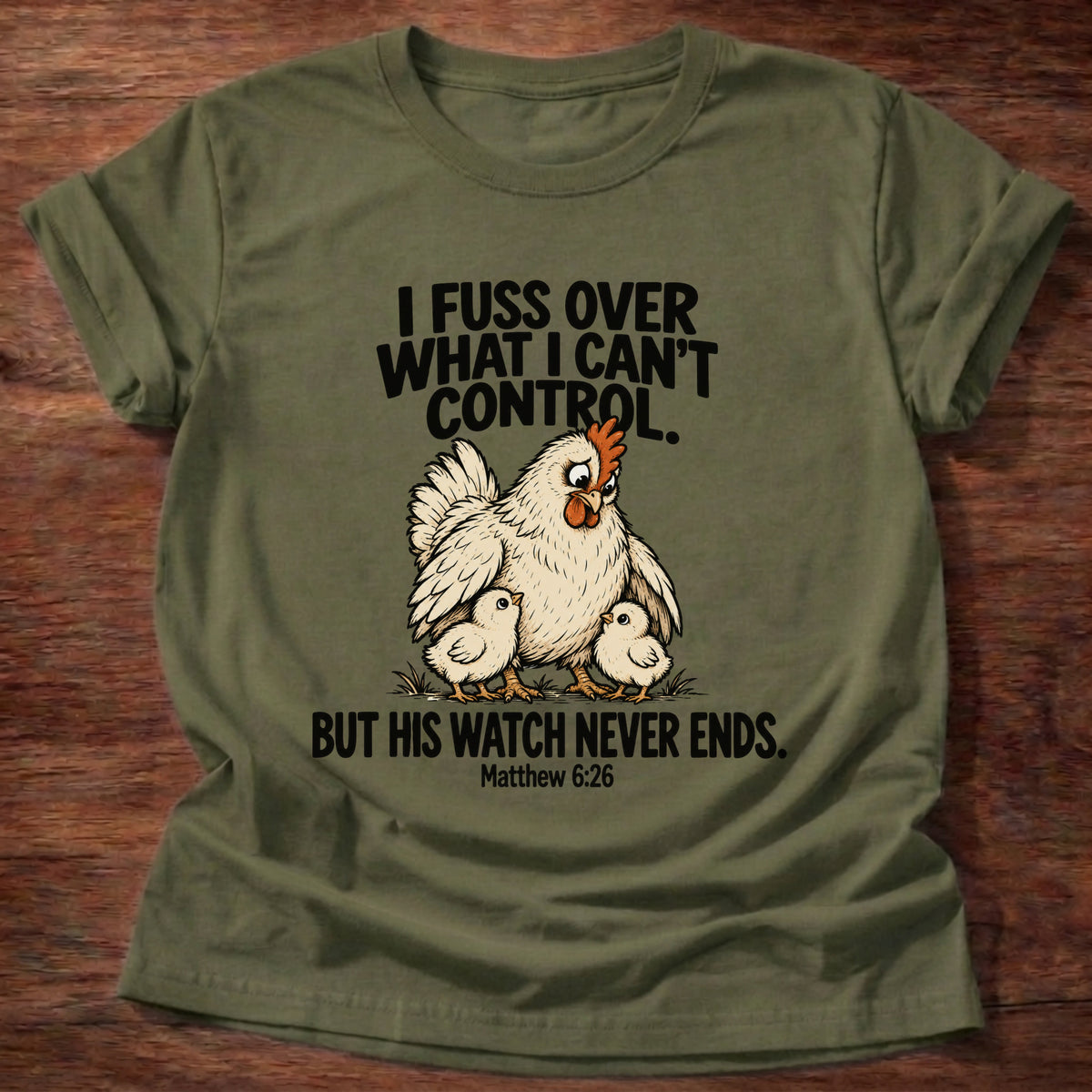 Military Green t-shirt printed with a fussing hen graphic and 'I fuss over what I can't control. But His watch never ends.' Matthew 6:26 faith based gift
